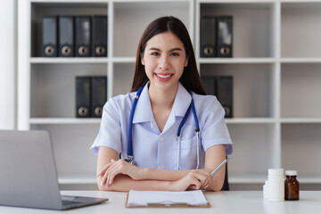 Smiling Happy and Beautiful Doctor working on laptop at clinic, health care, medical, healthy concept