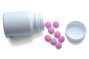 A jar with scattered pink pills lies on its side on a white background. The concept of treatment,...