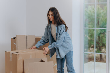 A woman packs her belongings in boxes to move to a new apartment. moving to a house. a girl stacks...