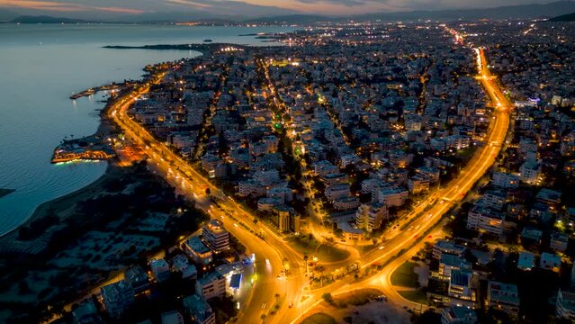Aerial time lapse view of the Athens Riviera coastline with Voula district, coastal road and Vouliagmenis street during dusk with traffic light trails, Greece