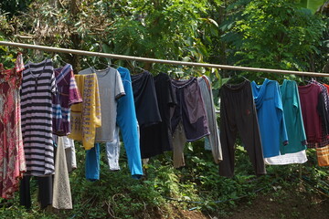 Drying clothes that have been washed manually using the sun.