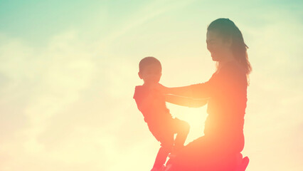 Mother encouraged her son outdoors at sunset, silhouette concept