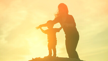 Fototapeta na wymiar Mother encouraged her son outdoors at sunset, silhouette concept