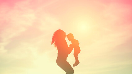 Mother encouraged her son outdoors at sunset, silhouette concept