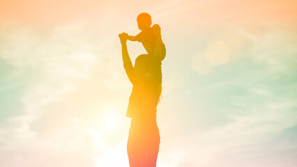 Mother encouraged her son outdoors at sunset, silhouette concept