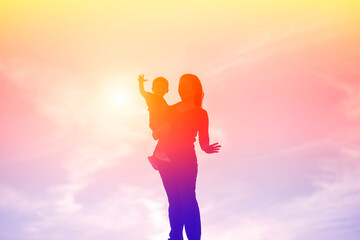 Mother encouraged her son outdoors at sunset, silhouette concept