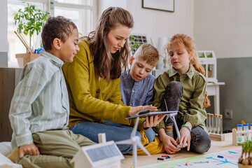Young teacher learning pupils about solar and wind energy.
