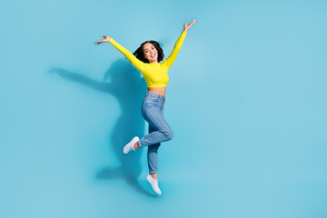 Full body portrait of overjoyed cheerful lady jumping raise arms empty space ad isolated on blue color background