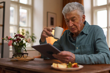 Senior man reading something in digital tablet.