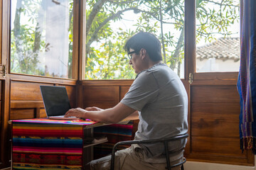 Digital nomad working in a cabin by the window typing on a laptop