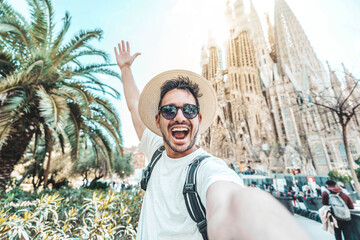 Happy tourist visiting La Sagrada Familia, Barcelona Spain - Smiling man taking a selfie outside on city street - Tourism and vacations concept - obrazy, fototapety, plakaty