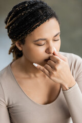 Young african american woman practicing nostril breathing and meditation in yoga studio.
