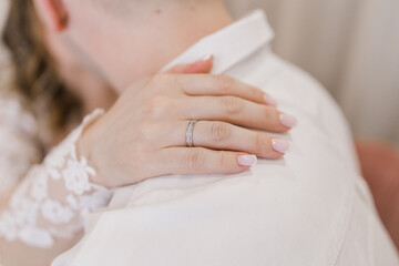 the bride puts her hand with the wedding ring on the groom's shoulder