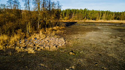 Aerial view of the fish pond with drained water and a river flowing on a sunny,winter day.