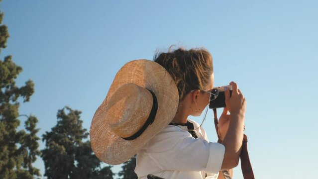 Young Woman taking pictures at Parthenon, Acropolis of Athens, Greece. Large hat, fashion white dress, sunglasses, vintage camera.