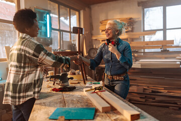 Joyful female carpenters shaking hands.