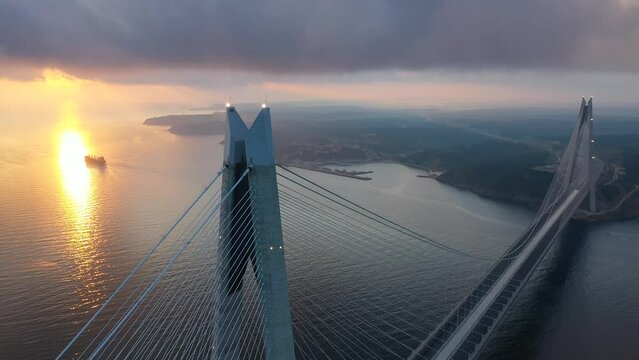 Sun rays reflect on the water under the dense cloud layer over the Bosphorus. Aerial view of Istanbul's 3rd cable bridge YSS at sunset. 
