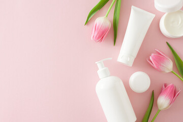 Obraz na płótnie Canvas Organic beauty products concept. Flat lay photo of cosmetic tubes without label cream jar and pink tulips on isolated pastel pink background with copyspace