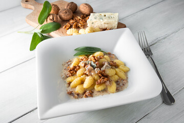 Piatto di deliziosi gnocchi di patate conditi con gorgonzola e noci, cibo italiano 