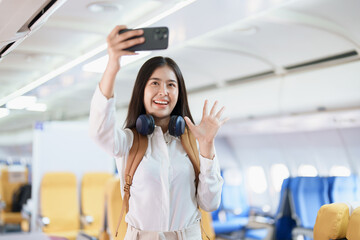 Asian business woman passenger sitting on business class luxury plane while working using smart phone mobile talking or video conference and travel concept