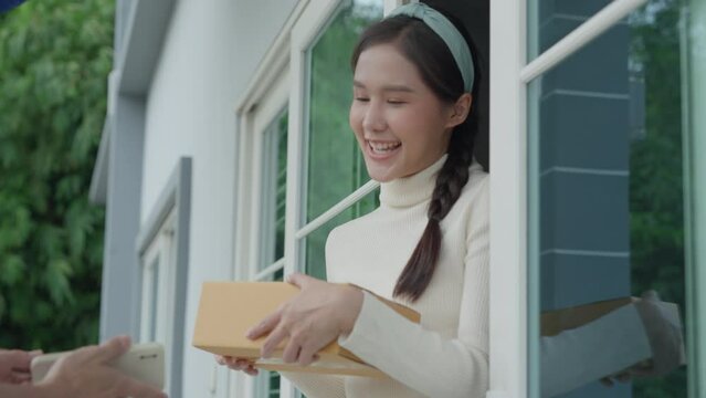 Happy smiling woman receives bag parcel from courier in front house. Delivery man send deliver express. online shopping, paper containers, takeaway, postman, delivery service, packages