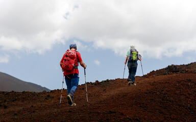Couple hiking a volcano in tenerife. Hikers with hiking clothing at the mountain. scenic hike