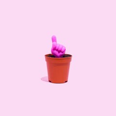 One finger up icon growing from a small pot on a pastel pink background. Hand gesture concept.