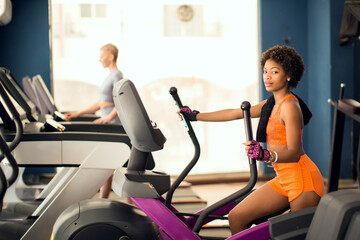 Fototapeta na wymiar Fitness woman using elliptical medicine in the gym. Health and lifestyle concept