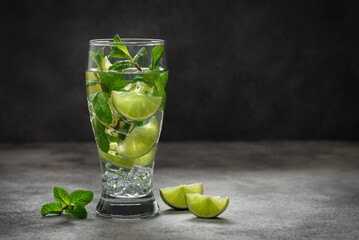Mojito cocktail. Summer refreshing mojito drink with ice, lime and fresh mint on a dark background....