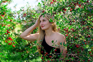 Attractive woman is in shadow of cherry branches with ripe berries.