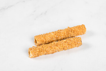 Two Waffle tubes glazed with white chocolate and sprinkled with crushed peanuts. White background. Close up