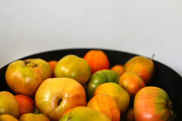Tomatoes collection close up. Tomatoes on white background. Beautiful red, yellow, green ripe heirloom tomatoes in bucket. Gardening and harvest concept. Out of focus