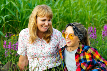 Defocus mother and daughter sitting on meadow and smiling. Friendship love concept. Woman and girl...