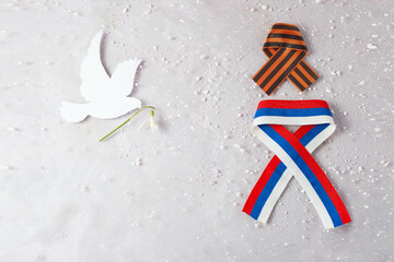 white dove made of paper next to the ribbons of Russia and the Ribbon of St. George
