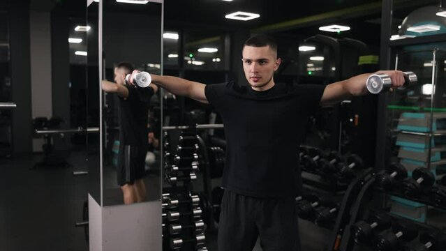 Exercise intensity, Workout variations, Dumbbell safety. Powerful man partakes in gym-based functional training with dumbbells, working hard to develop his muscles and enhance his overall fitness