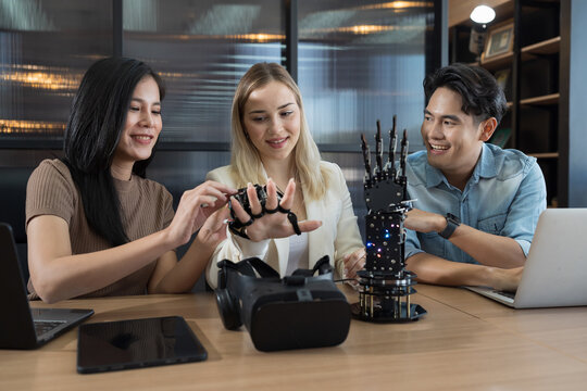 Young male and female working with AI robot arm system project in workshop. Male engineer using laptop computer for training Programmable logic controller robotics arm system project