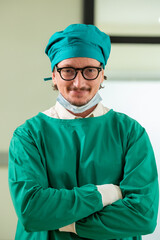 Man male surgeon doctor portrait in Green coat gown with stethoscope, waist up. Medical senior attractive friendly smiling clinic arms crossed wear Green lab coat stand in hospital patient room