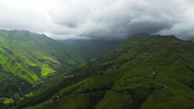 Aerial view of green valley with high mountains and gray clouds in the sky. Sun rays over the slope. Aragua state, Venezuela