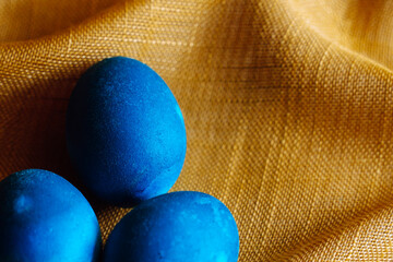 Group of three blue dyed easter eggs on golden textired background