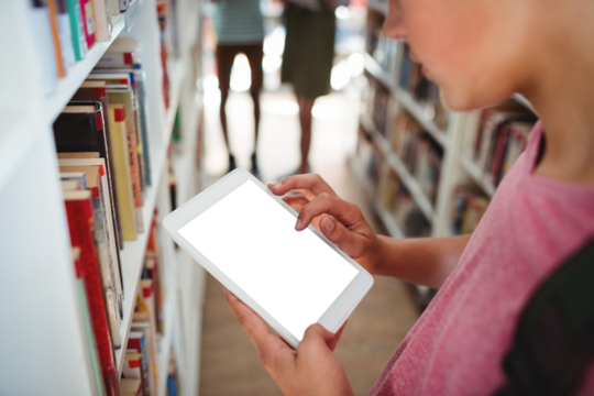 Schoolboy using digital tablet in library