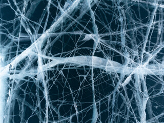 The natural texture of winter ice with white bubbles and cracks on a frozen lake. Abstract background of ice and cracks on the surface of frozen Lake Baikal