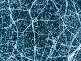 The natural texture of winter ice with white bubbles and cracks on a frozen lake. Abstract background of ice and cracks on the surface of frozen Lake Baikal