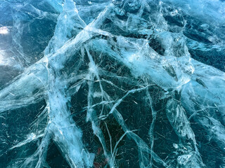 The natural texture of winter ice with white bubbles and cracks on a frozen lake. Abstract background of ice and cracks on the surface of frozen Lake Baikal