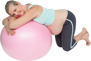 Cheerful pregnant woman kneeling against pink exercise ball