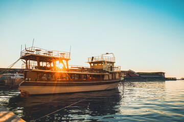 Obraz premium Beautiful vintage yacht at beautiful sunset on the embankment of the Konak district in Izmir, Turkey.