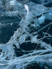 The natural texture of winter ice with white bubbles and cracks on a frozen lake. Abstract background of ice and cracks on the surface of frozen Lake Baikal