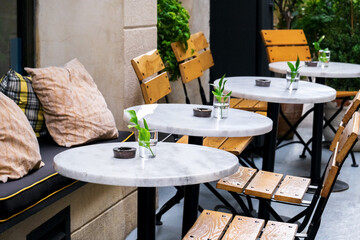 Horizontal photo of an empty terrace of a modern cafe. The interior of the coffee shop with wooden chairs and marble tables.