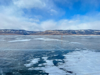 Fototapeta premium pure ice of the frozen lake Baikal against the background of mountains. frozen winter Baikal