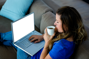 Business woman sipping coffee while using typing on her laptop