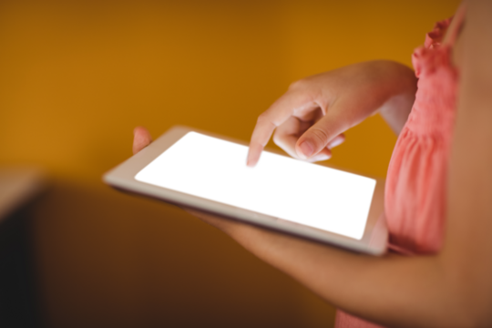 Young girl using digital tablet while standing